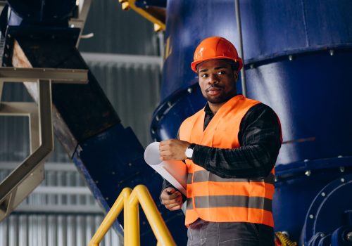 African american worker standing in uniform wearing a safety hat in a factory
